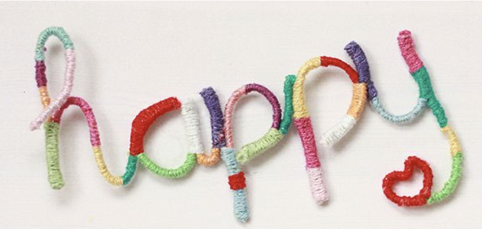 Colourful yarn-wrapped wire spells “happy” with a small red heart, displayed on a white background.